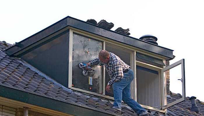 Man installing double glazing on a dormer window to improve insulation and energy efficiency in a home.